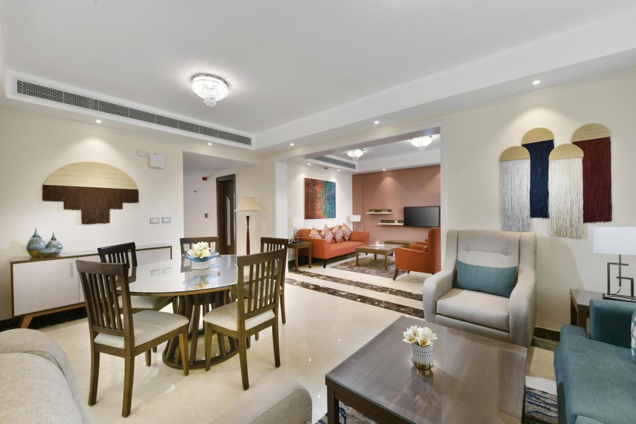 Tolip Resort El Galala Majestic Ain Sukhna Luaran gambar The photo shows a modern living room space that is elegantly designed. It features a seating area with a comfortable sofa and armchairs, complemented by a decorative coffee table. There is a dining table with several wooden chairs, providing a cozy a