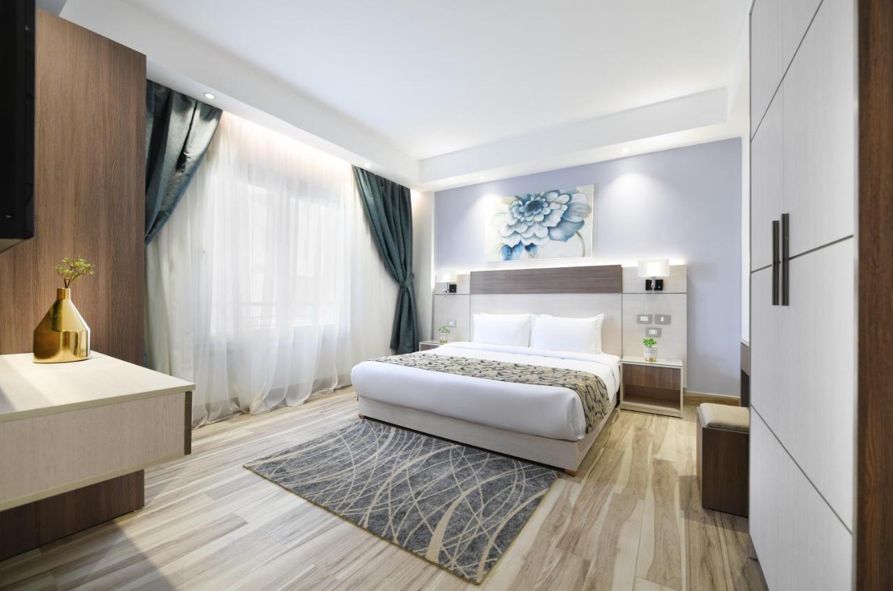 Tolip Resort El Galala Majestic Ain Sukhna Luaran gambar The photo shows a modern bedroom with a clean and stylish design. It features a large bed with white bedding positioned against a wall. Above the bed, there is a decorative artwork, possibly a floral design. The room has large windows with sheer curt