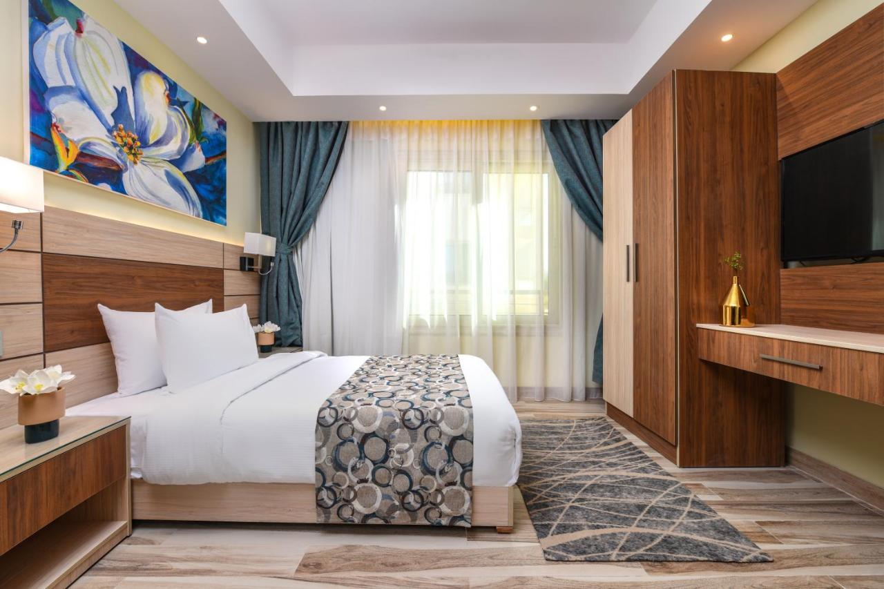Tolip Resort El Galala Majestic Ain Sukhna Luaran gambar The photo shows a well-designed hotel room. It features a comfortable bed with a decorative bedspread and two pillows. There are soft curtains framing a window that lets in natural light. On one side, there is a colorful piece of artwork hanging on t