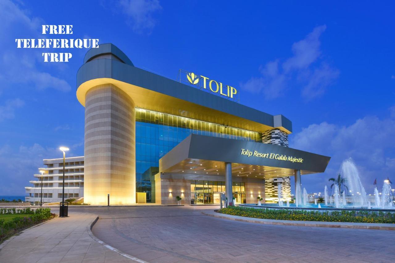 Tolip Resort El Galala Majestic Ain Sukhna Luaran gambar The photo shows a modern hotel building named "Tolip Resort & Spa," featuring a sleek architectural design with large glass windows. The hotel is illuminated against a twilight sky, showcasing its prominent signage. In the foreground, there is a well