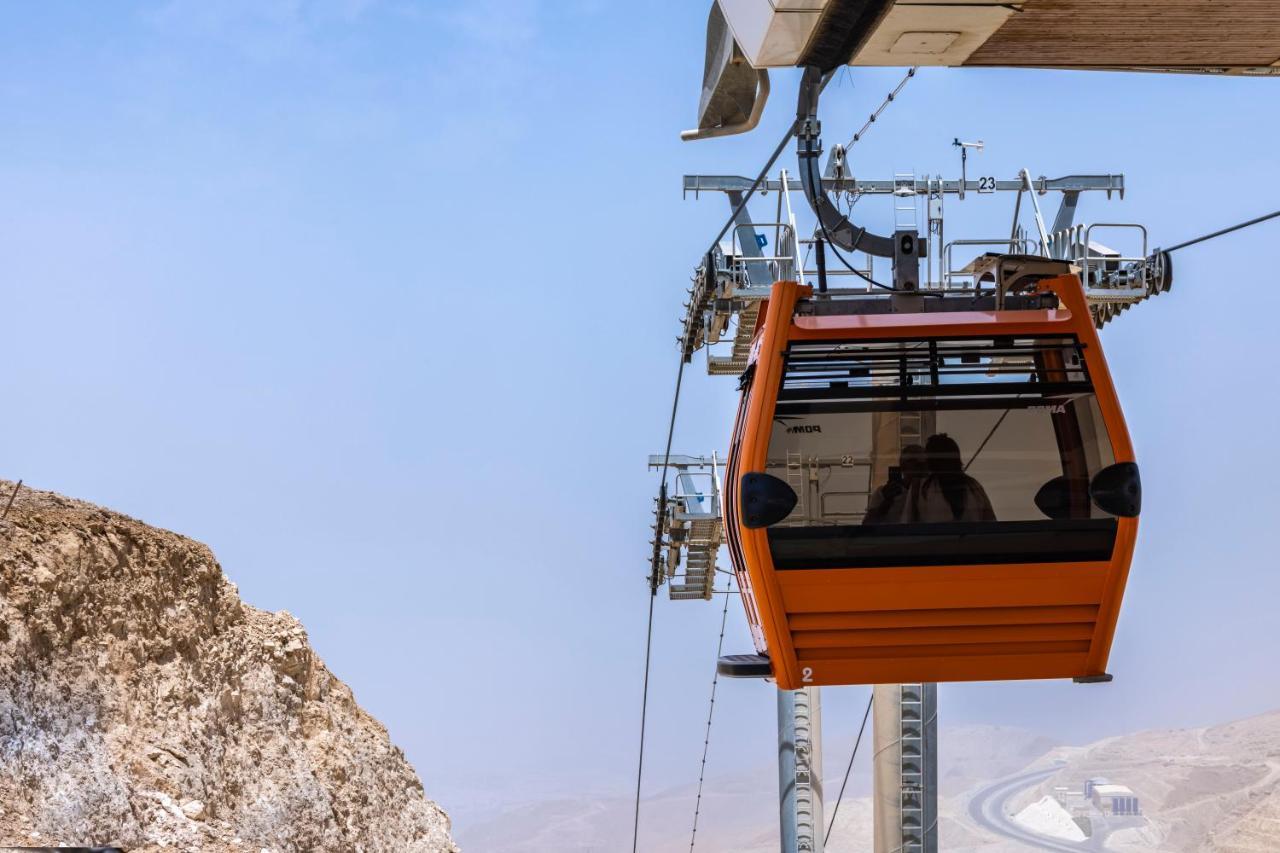 Tolip Resort El Galala Majestic Ain Sukhna Luaran gambar The photo shows an orange gondola or cable car hanging on a cable system. The gondola appears to be suspended in the air above a rocky landscape, with a clear sky in the background. There are supporting cables and structures visible, indicating that 