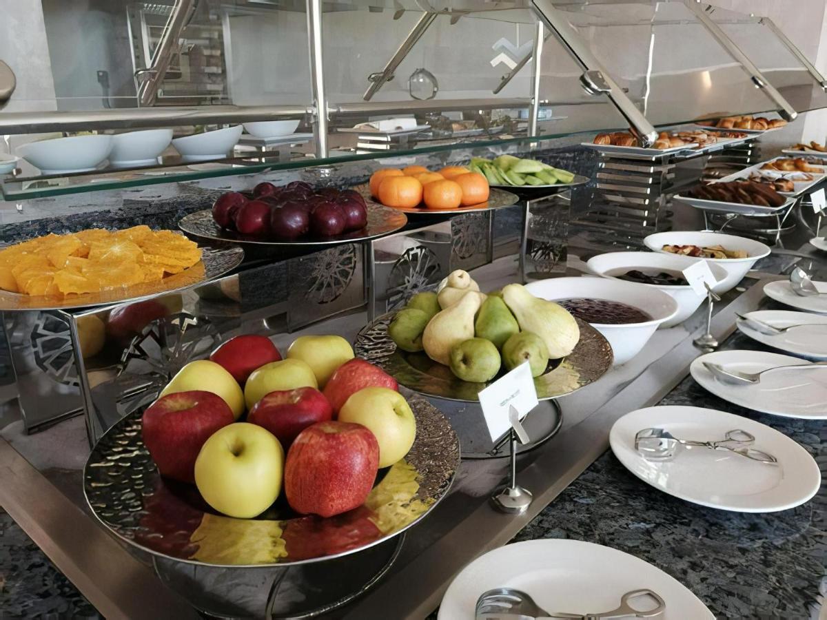 Tolip Resort El Galala Majestic Ain Sukhna Luaran gambar The photo displays a buffet setup featuring an assortment of fresh fruits arranged on several tiered trays. There are red and green apples, pears, grapes, and oranges. Adjacent to the fruit display, there are several bowls containing various other fo