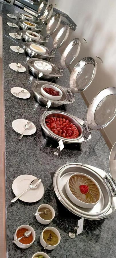 Tolip Resort El Galala Majestic Ain Sukhna Luaran gambar The photo shows a buffet setup featuring multiple metal serving trays on a dark granite countertop. One tray contains circular slices of food, possibly sausages or a similar dish, while another bowl holds what appears to be red food items, though it'