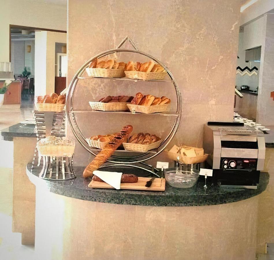Tolip Resort El Galala Majestic Ain Sukhna Luaran gambar The photo shows a display of various types of bread and pastries arranged on a countertop. There are several baskets stacked on a circular stand, filled with different baked goods like croissants and rolls. A long baguette is placed horizontally on a