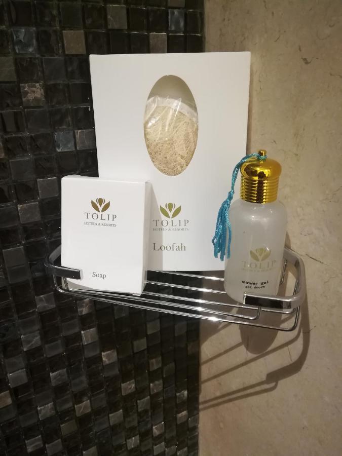 Tolip Resort El Galala Majestic Ain Sukhna Luaran gambar The photo shows a small metal shelf containing three items related to personal care. 

1. **Soap**: A white box labeled "TOLIP" with the word "Soap" visible on the front.
2. **Loofah**: A package with the same "TOLIP" branding, containing loofah.
3. 